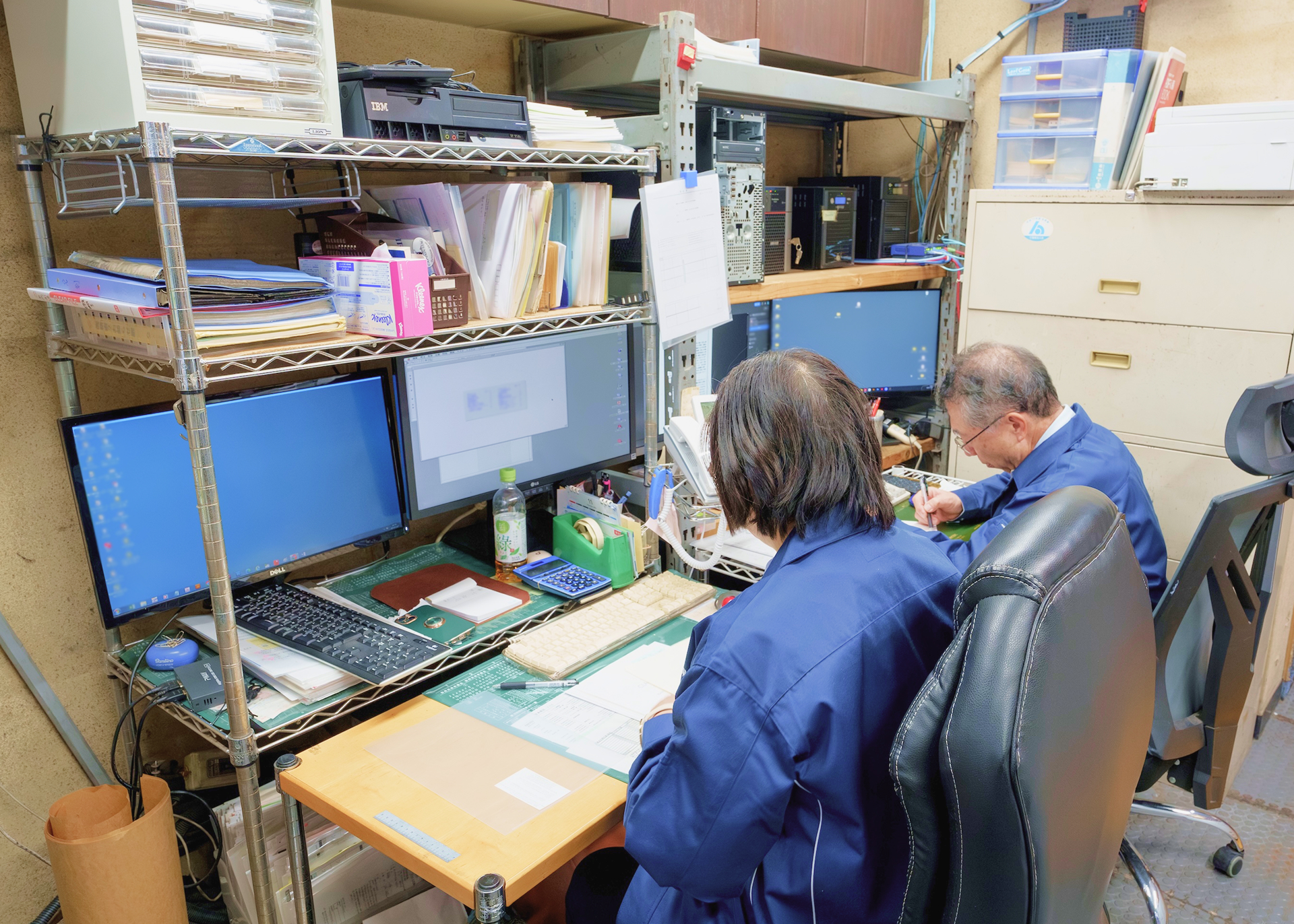 遠藤印刷の机とパソコン前に座る女性と男性