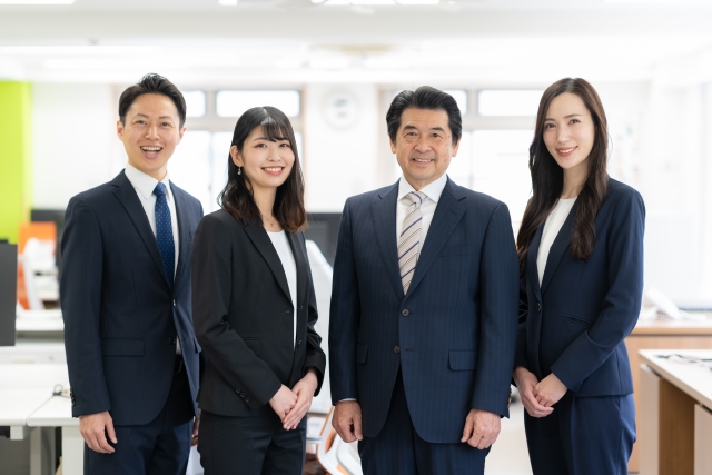 オフィスでスーツを着て立つ4人